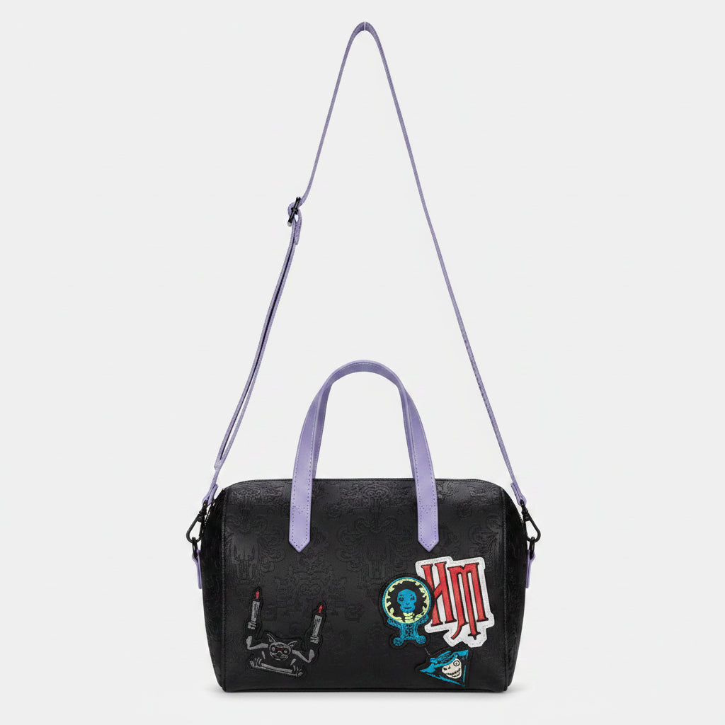 Black handbag with colorful patches and a purple strap on a white background